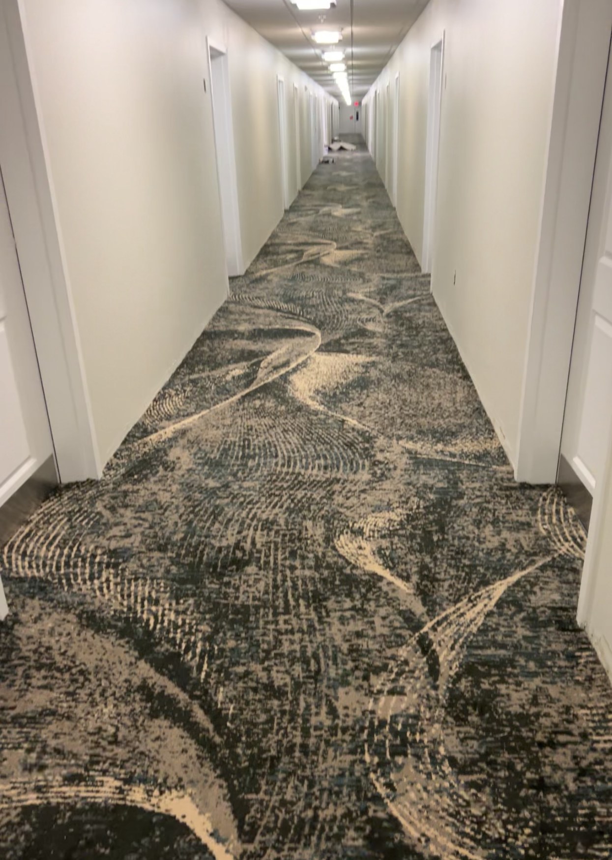 Patterned carpet installed down a long hotel corridor